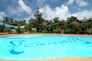 A swimming pool with a tropical resort setting, including palm trees and covered structures. - Lanta Emerald Bungalow (Ko Lanta)