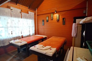 A room with two beds, each with a towel and a pillow, and a wooden wall with artwork. - Baan Laanta Resort and Spa (Ko Lanta)