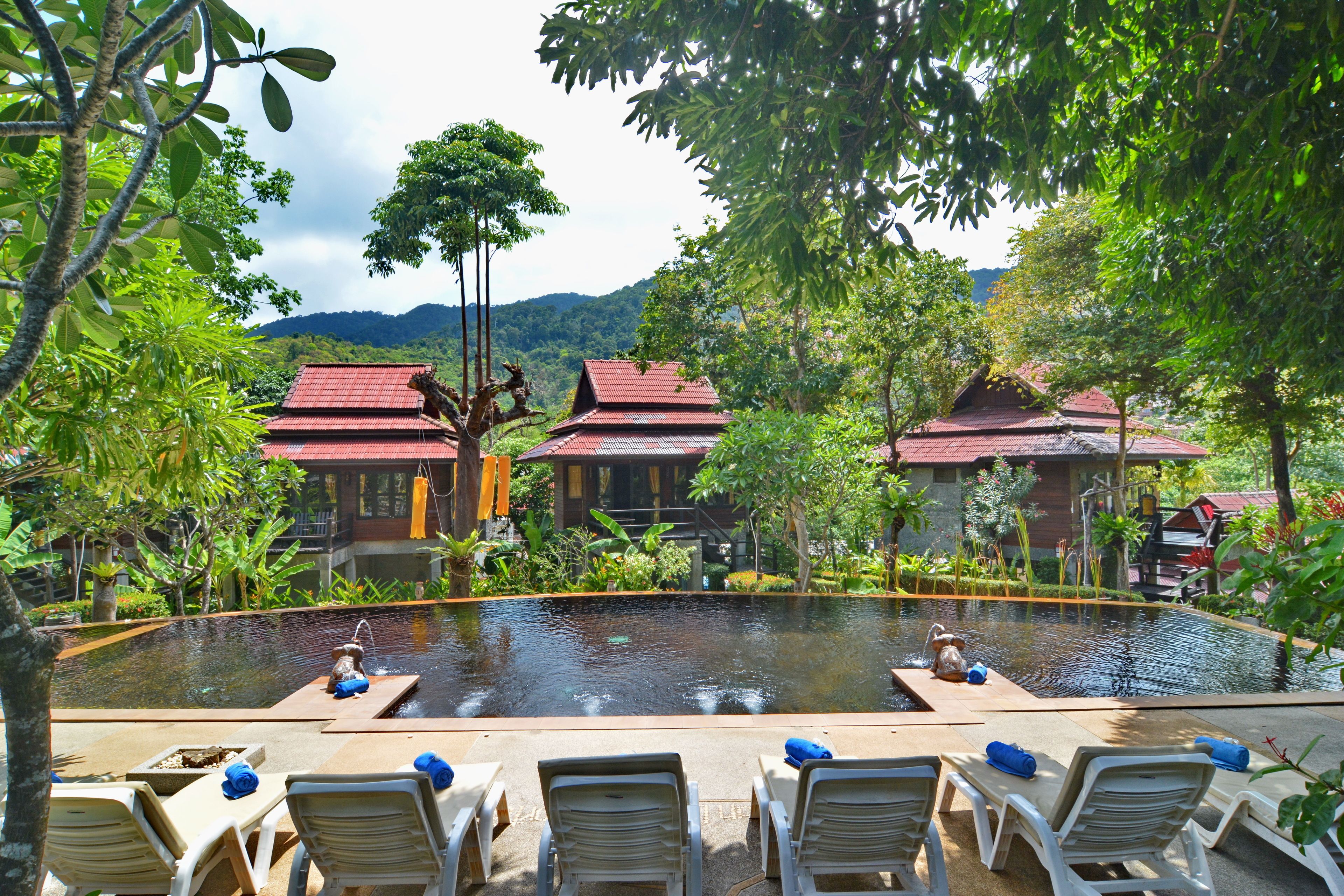 Área de piscina com espreguiçadeiras e vista para edifícios tradicionais.