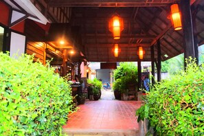 A covered walkway with potted plants on either side, leading to a building with a tiled entrance. - Baan Laanta Resort and Spa (Ko Lanta)