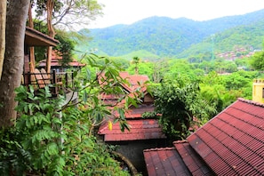 A traditional building with red-tiled roofs, surrounded by lush greenery and hills in the background. - Baan Laanta Resort and Spa (Ko Lanta)