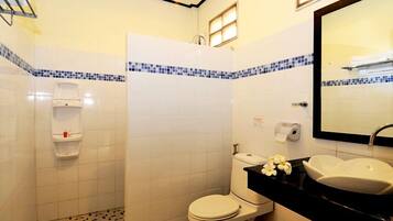 A bathroom with a toilet, bidet, sink, and mirror.