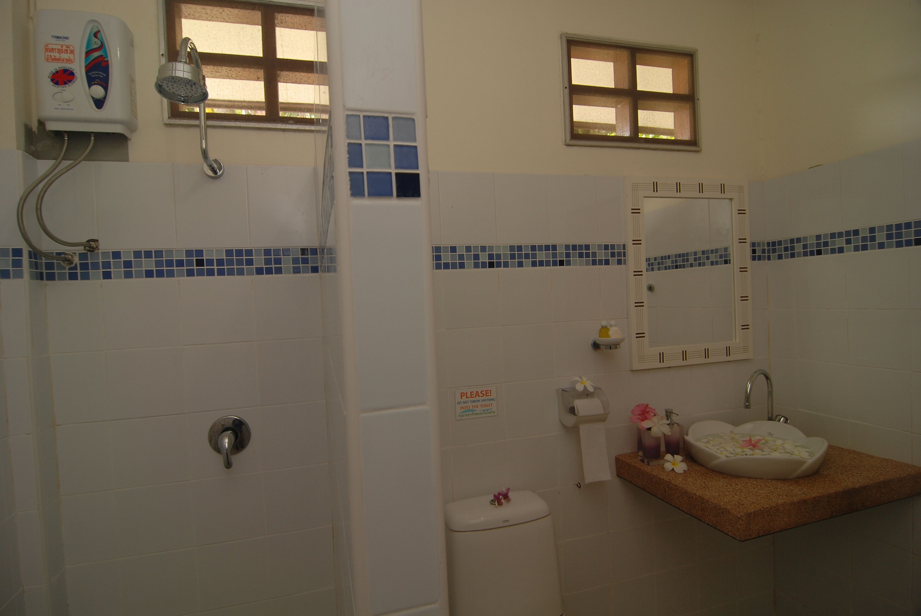 A bathroom with a shower, toilet, sink, and a mirror.
