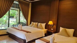 Una habitación de hotel con dos camas, una ventana con cortinas, una mesita de noche con lámpara y vistas al exterior a zonas verdes.