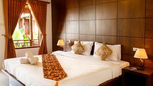 A neatly made bed with white linens and decorative pillows, a wooden headboard, and a nightstand with a lamp. -  Baan Rabieng (Ko Lanta)