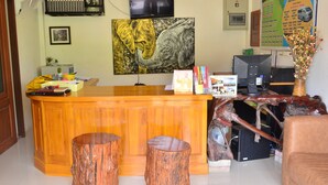 A reception desk with a wooden finish, a mounted television, and a large elephant painting on the wall. -  Baan Rabieng (Ko Lanta)