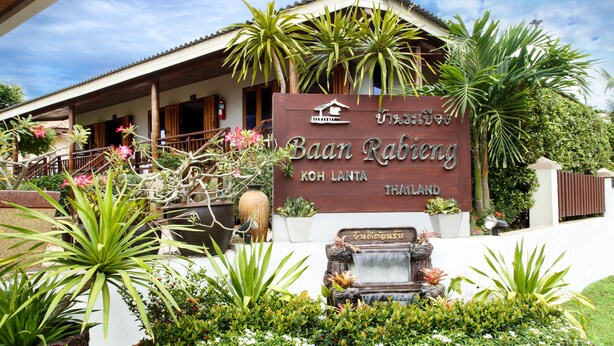 A sign for Baan Rabiang Koh Lanta, Thailand, with a wooden structure and lush greenery. -  Baan Rabieng (Ko Lanta)