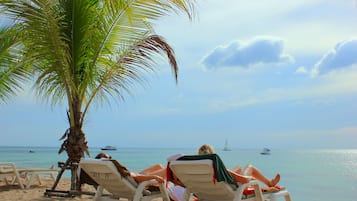 Na praia, areia branca, guarda-sóis, toalhas de praia
