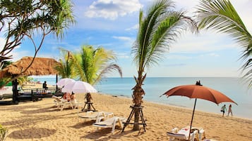 Na praia, areia branca, guarda-sóis, toalhas de praia