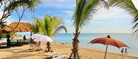 På stranden, vit sandstrand, parasoller och strandhanddukar