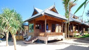 Een houten strandhuis met een veranda en een trap naar de ingang.