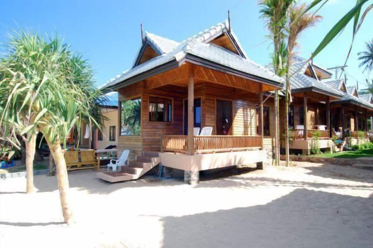 Ein Holzstrandhaus mit Veranda und einer Treppe zum Eingang.