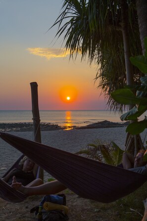 A hammock on a beach with a sunset in the background. - Lanta Coral Beach Resort (Ko Lanta)