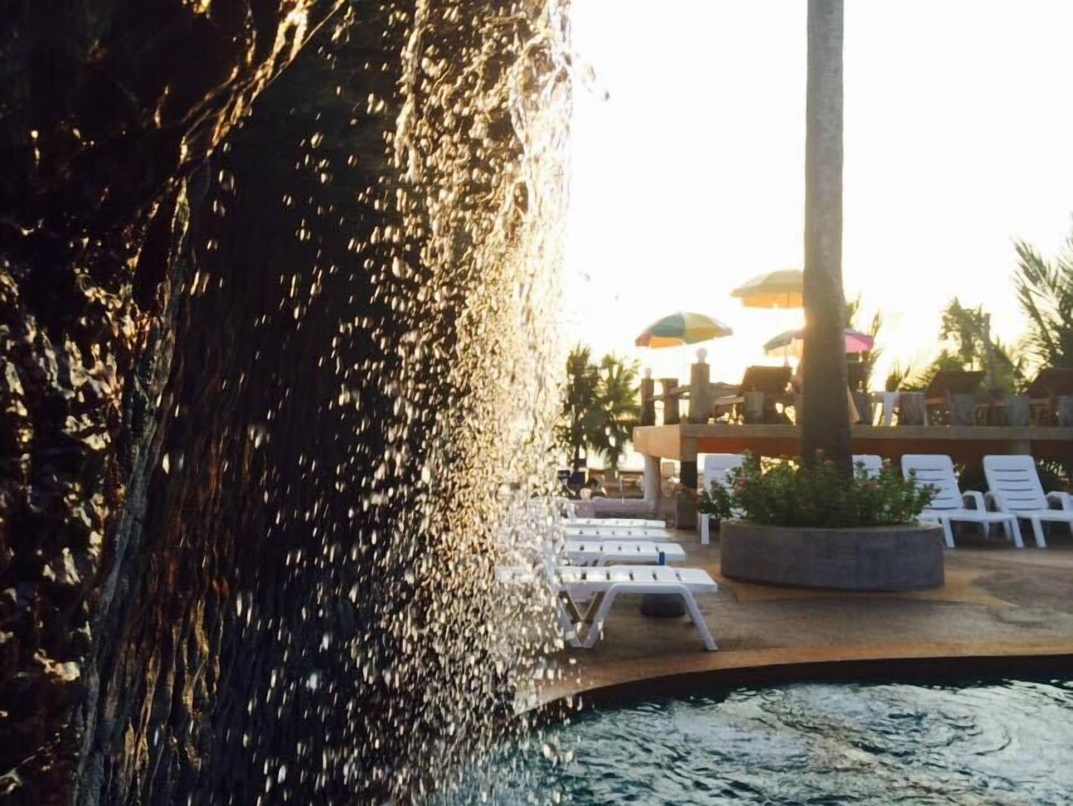 Una piscina al aire libre, sombrillas, sillones reclinables de piscina