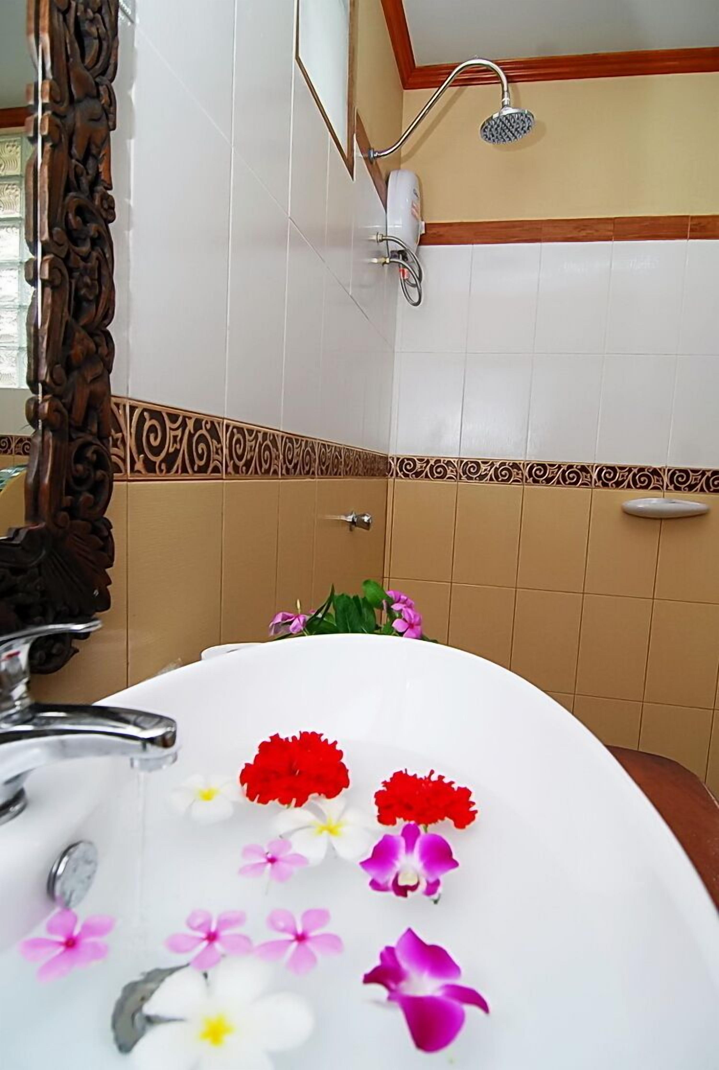 A bathroom with a white sink, a shower, and a mirror with an ornate frame.