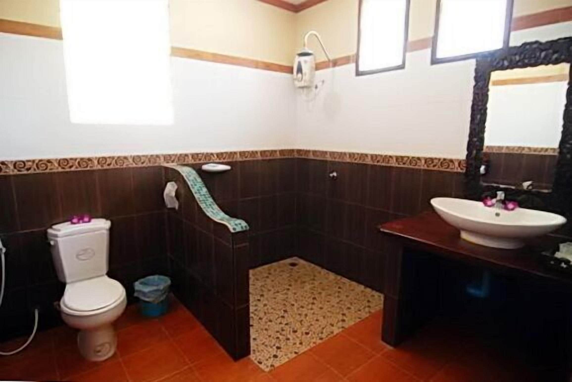 A bathroom with a toilet, sink, shower, and a patterned rug.