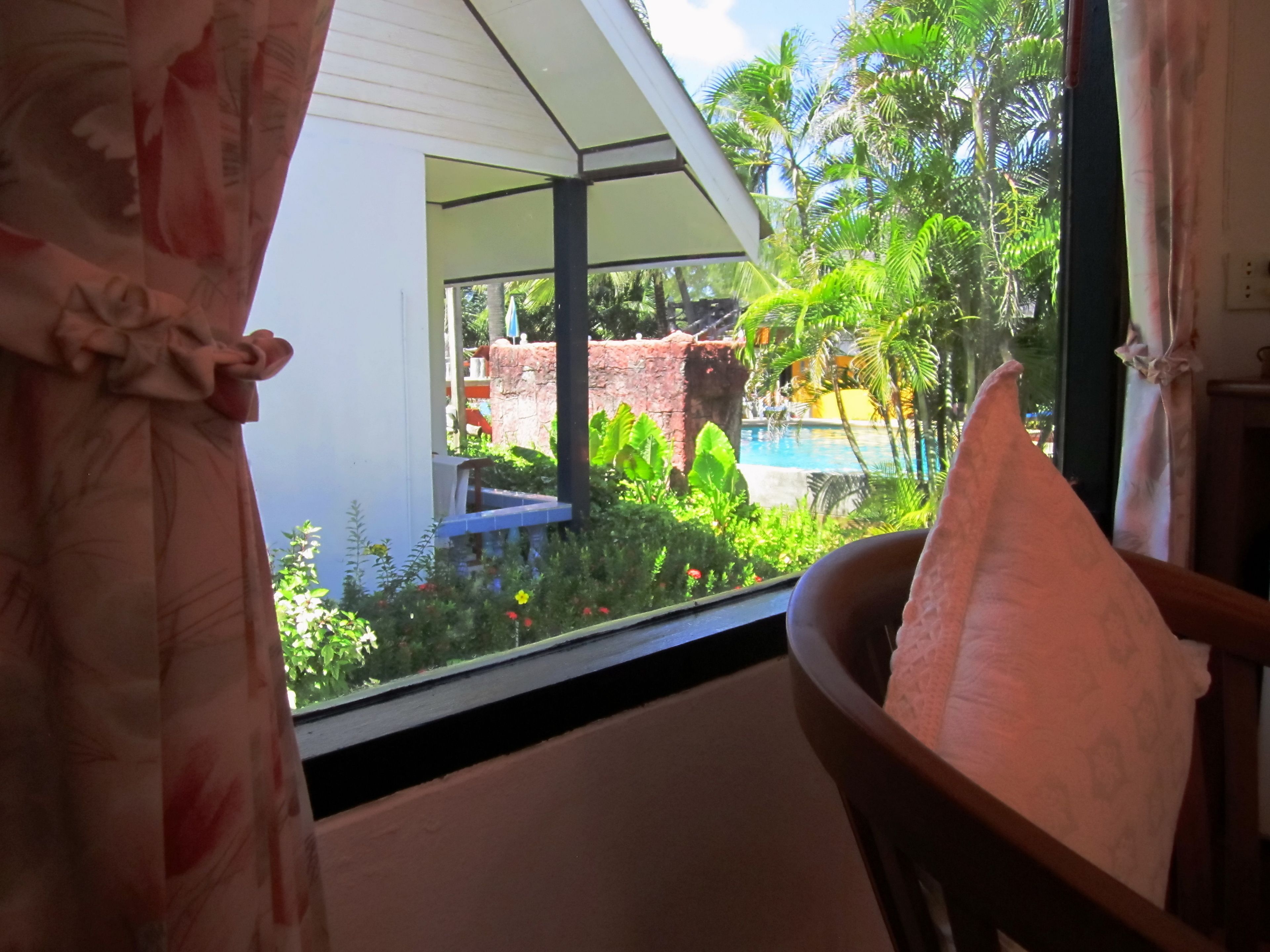 A room with a view of a pool and lush greenery outside.