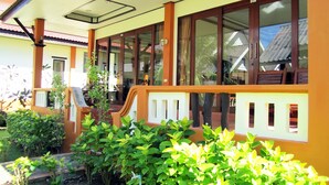 A building with large windows, a covered porch, and a small garden area.