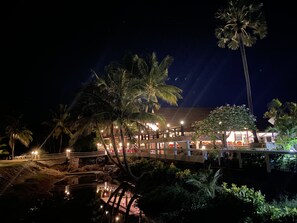 A waterfront hotel with a bridge, palm trees, and a reflection in the water. - Lanta Il Mare Beach Resort (Ko Lanta)