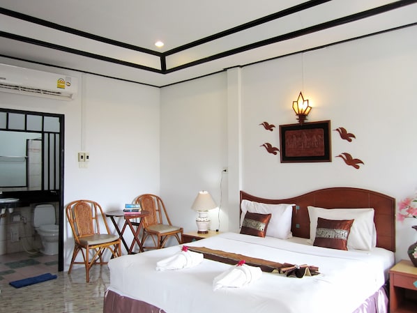 Habitación de hotel con cama, dos sillas, una mesa, una lámpara y un aplique de pared.