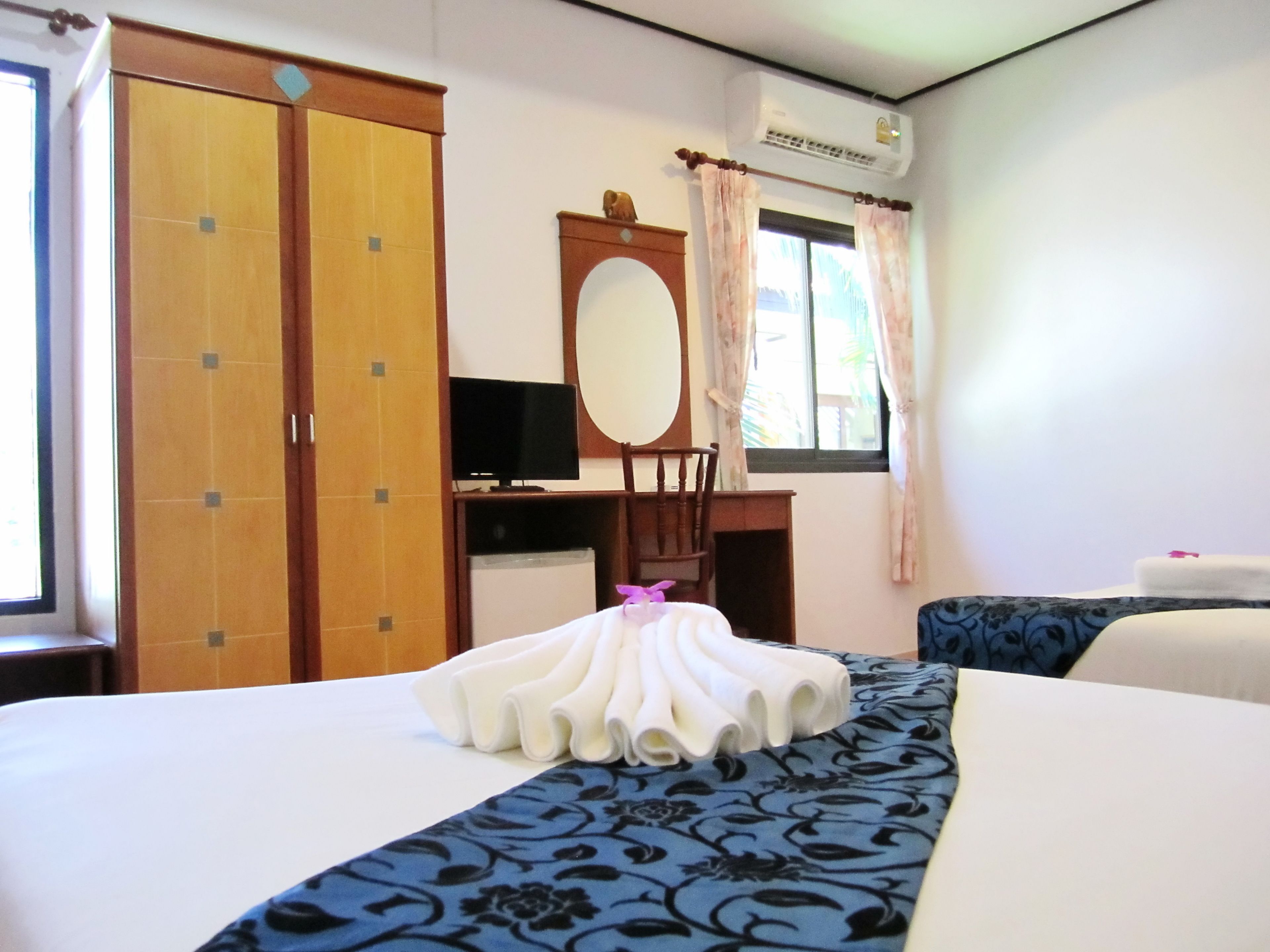 Et hotelværelse med seng, skrivebord med computer, garderobeskab og aircondition.