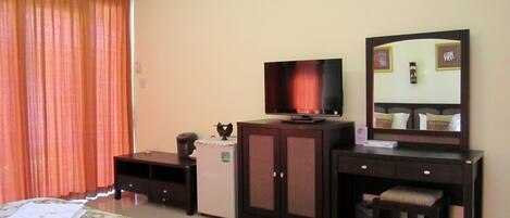 A hotel room with a bed, a television, a dresser, a mirror, and a small table.