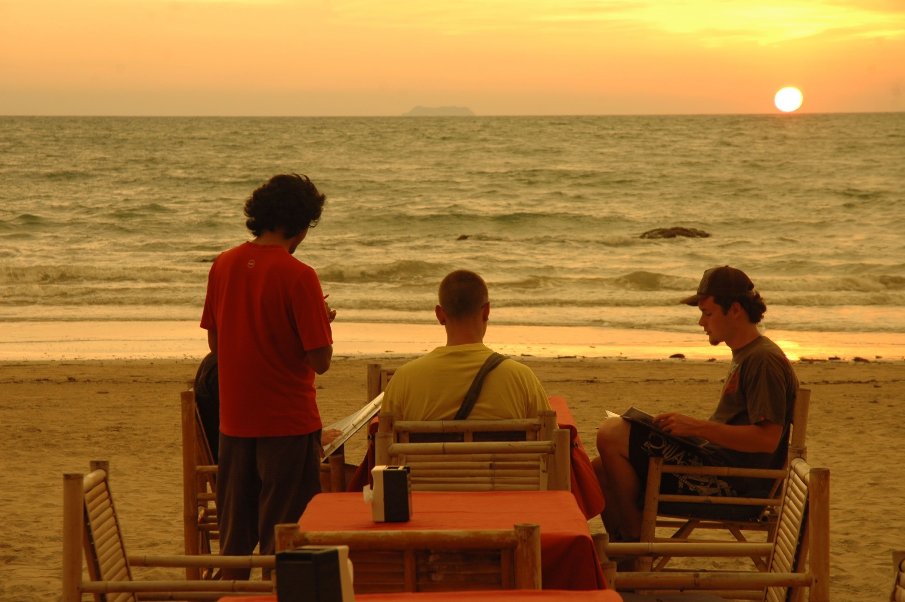A beachside restaurant with a table and chairs, overlooking the ocean.