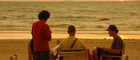 A beachside restaurant with a table and chairs, overlooking the ocean.