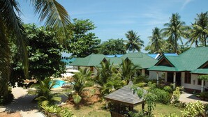 Un complexe hôtelier comprenant plusieurs bâtiments de style bungalow, une piscine et une végétation tropicale luxuriante.