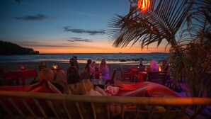 Un restaurant situé en bord de mer, avec une terrasse offrant une vue sur l’océan au coucher du soleil.