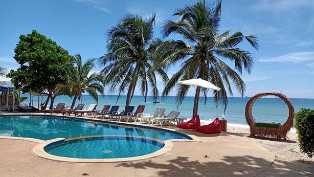 A pool area with lounge chairs, palm trees, and a view of the ocean. - Lanta Paradise Beach Resort (Ko Lanta)
