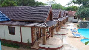 A row of bungalow-style accommodations with a swimming pool and lounge chairs. - Lanta Paradise Beach Resort (Ko Lanta)