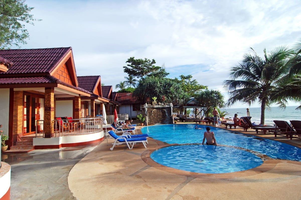 A resort with a swimming pool, lounge chairs, and a view of the ocean.