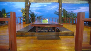 An outdoor dining area with a wooden table and benches, surrounded by a red railing and potted plants. - Lanta Paradise Beach Resort (Ko Lanta)