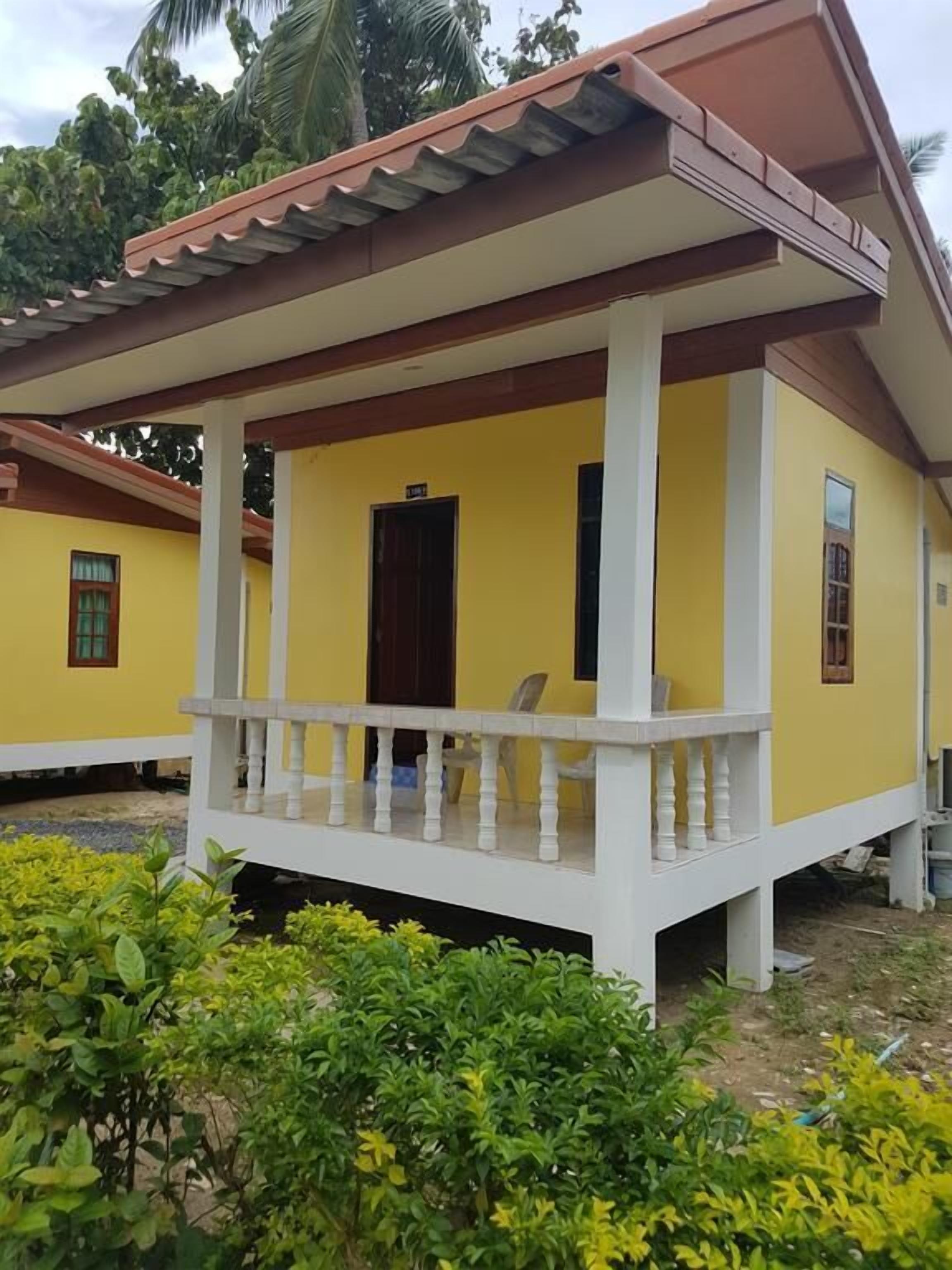 Un bâtiment jaune avec un porche et une porte.