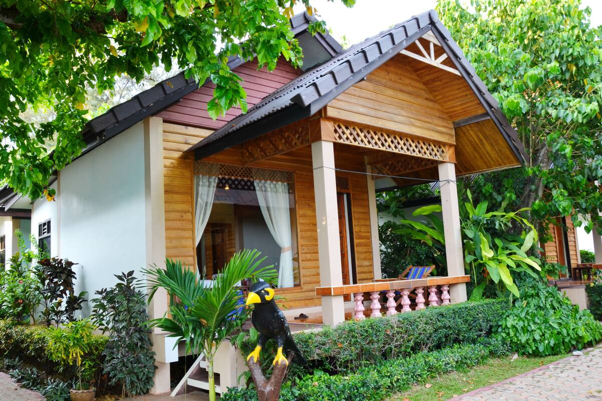 A wooden house with a porch and a birdhouse.