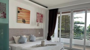 Une chambre à coucher moderne avec un grand lit, une porte-fenêtre coulissante donnant sur un balcon et des œuvres d’art accrochées aux murs.
