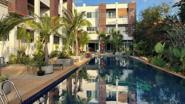 Un hôtel moderne doté d’une piscine entourée de palmiers et de verdure.