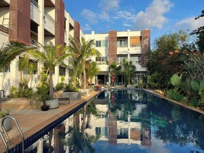 Un hôtel moderne doté d’une piscine entourée de palmiers et de verdure.