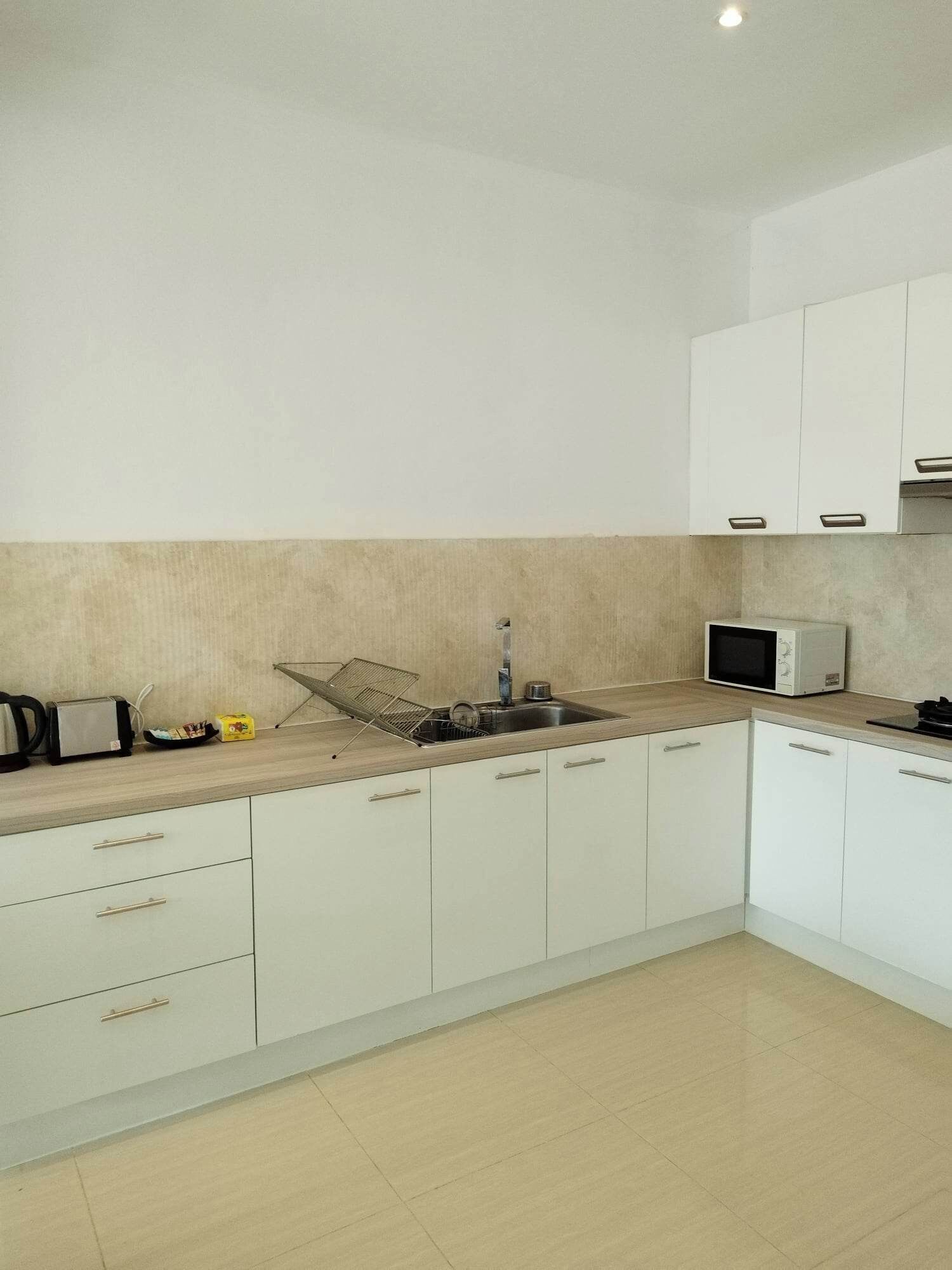 A kitchen with white cabinets, a sink, a microwave, and a toaster.