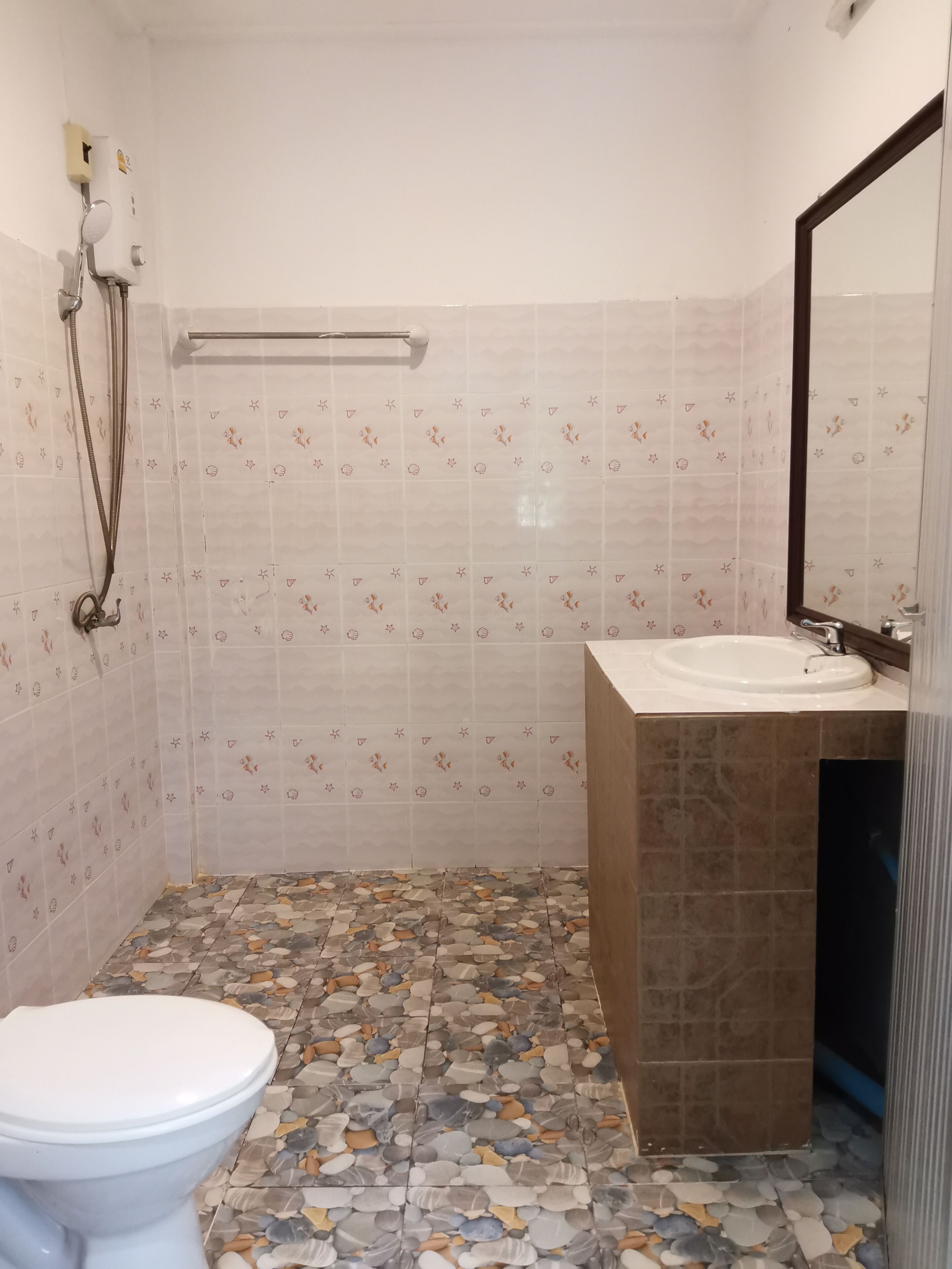 Un bany amb vàter, rentapel, dutxa i parets de rajola.