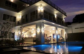 Un bâtiment moderne à deux étages doté d’une piscine, d’un espace extérieur aménagé et d’un bar.