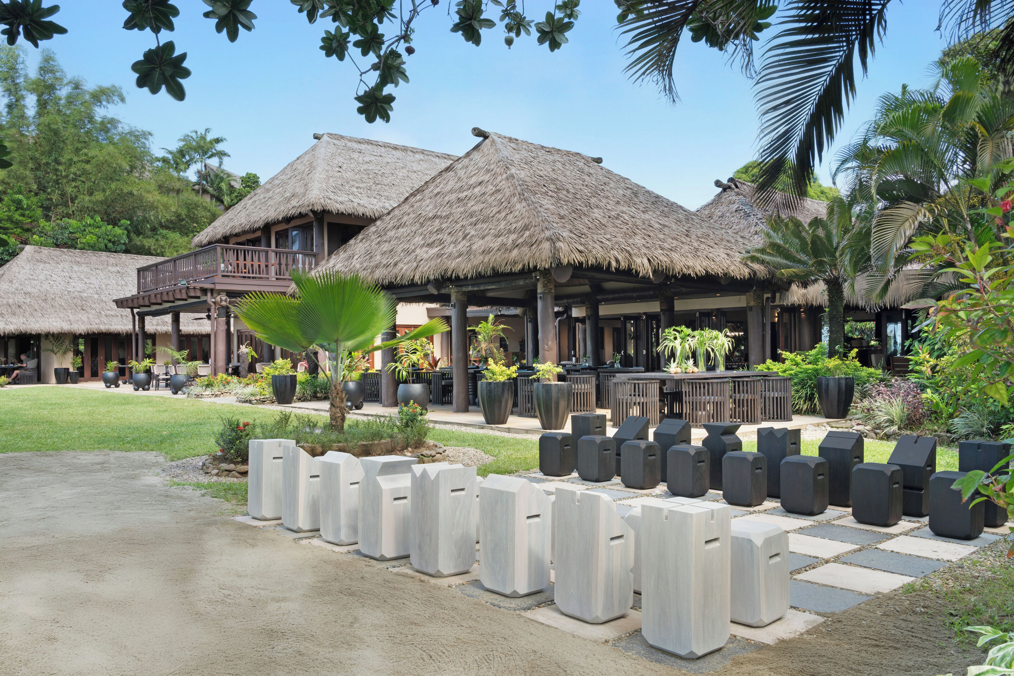 Un resort con edificios de techo de paja, asientos al aire libre y un jardín bien cuidado.