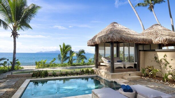 A pool area with lounge chairs and a thatched-roof structure, overlooking the ocean. - Nanuku Resort Fiji (Pacific Harbour)