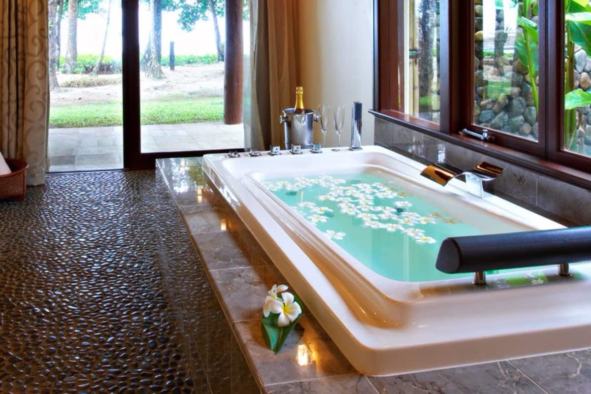 A spa room with a large bathtub, a bottle of champagne, and a glass of champagne.