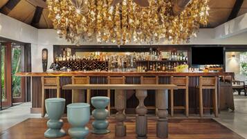 Zona de bar con mostrador de madera, diferentes botellas y una lámpara colgante original.