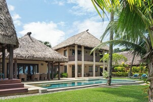Un complejo turístico con edificios de techo de paja, una piscina y zonas de estar al aire libre.