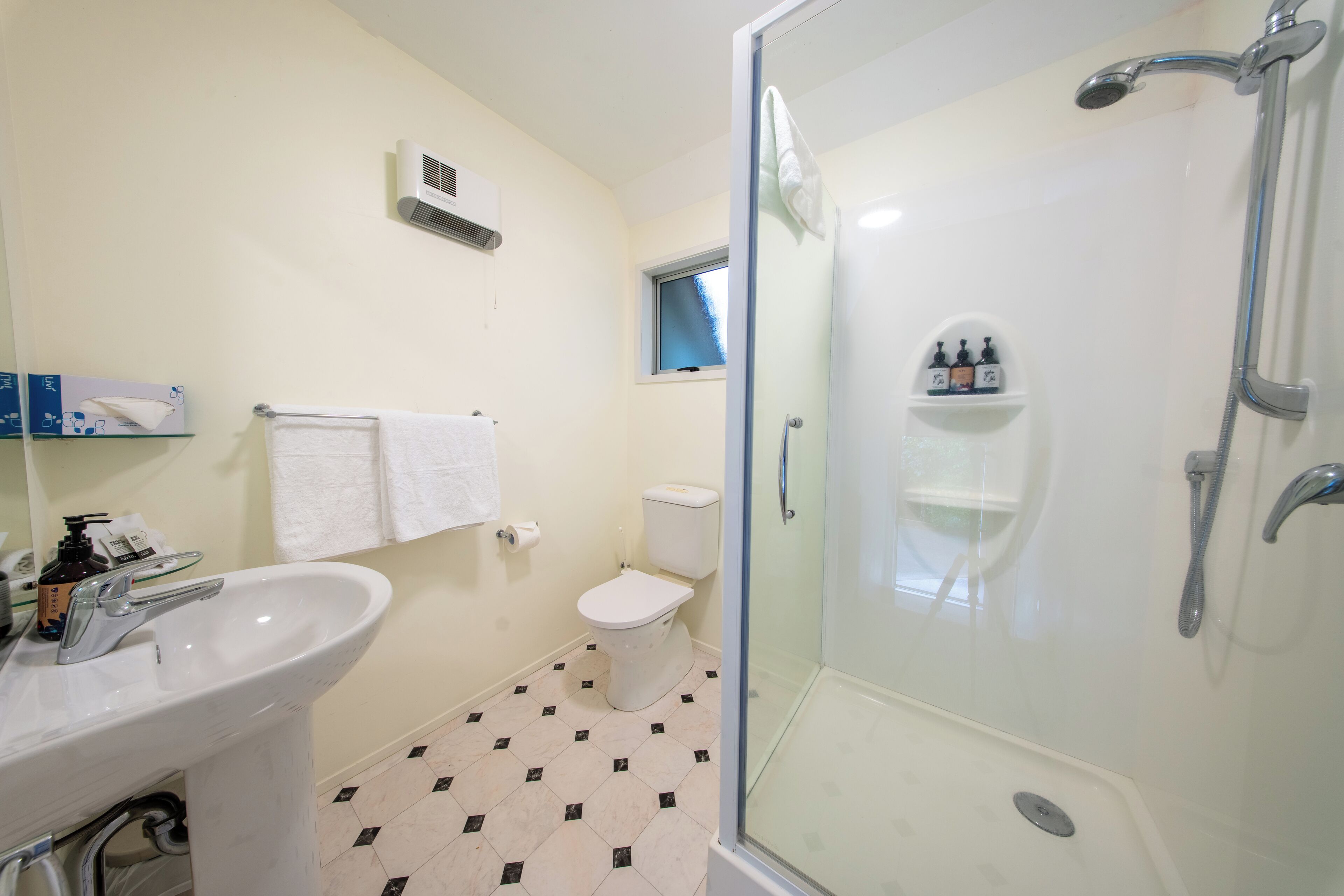 A bathroom with a glass-enclosed shower, a white sink, and a toilet.