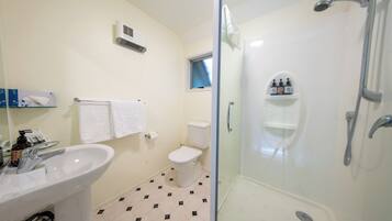 A bathroom with a glass-enclosed shower, a white sink, and a toilet.