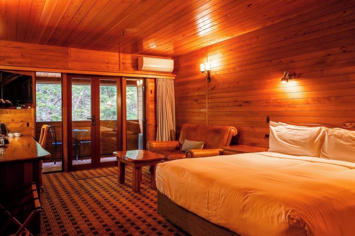 Une pièce de cabane en bois comprenant un lit, un bureau et une chaise.